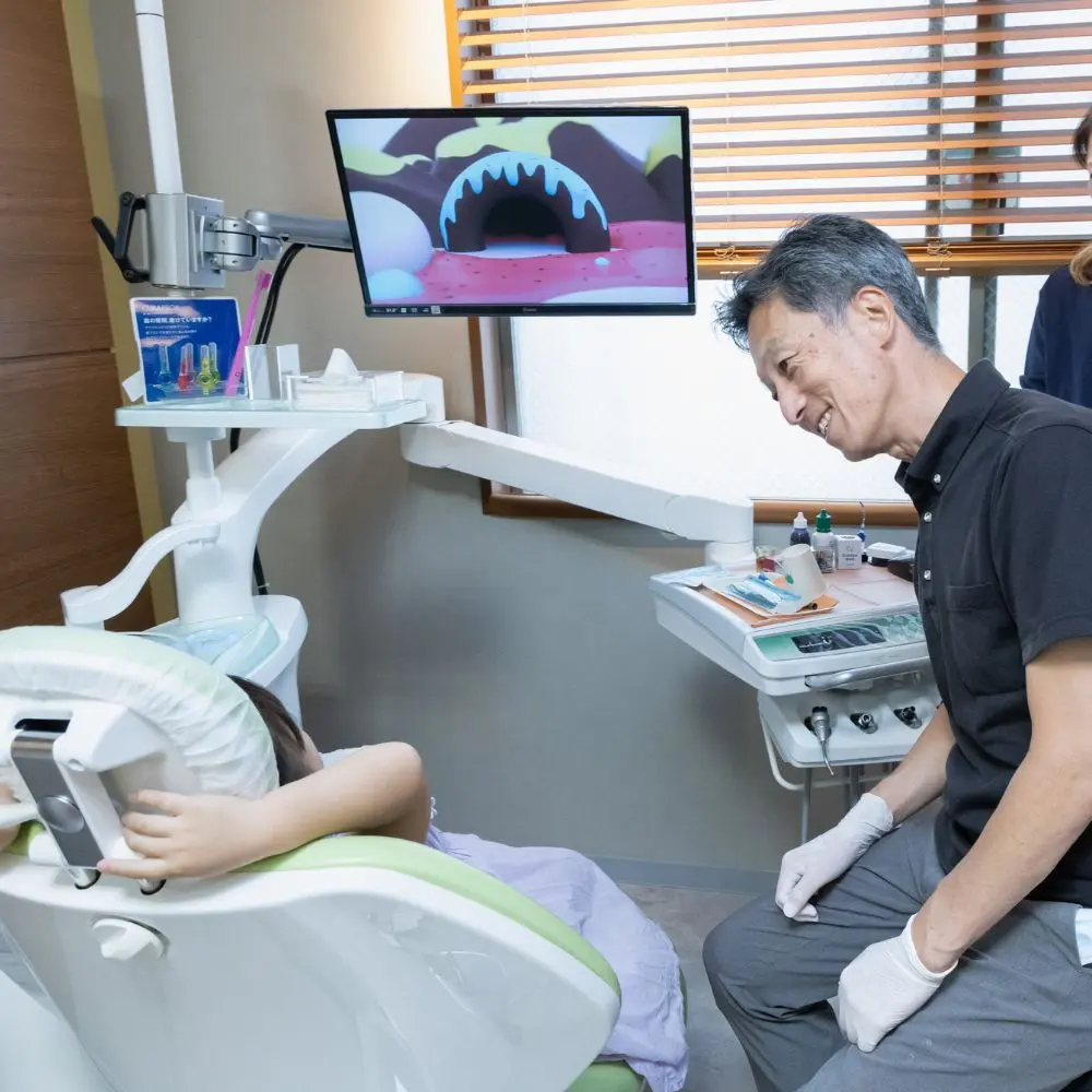 永沢デンタルクリニック院長が小児の患者と笑顔で会話している
