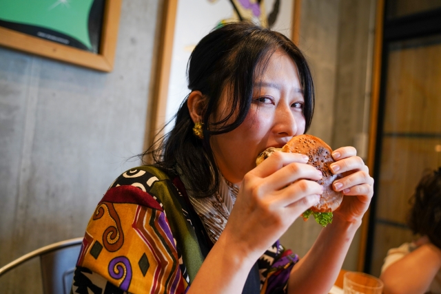 大きなハンバーガーを頬張る女性
