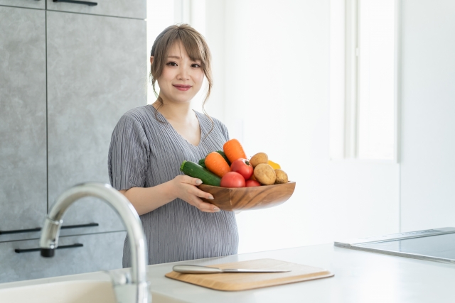 キッチンで野菜を持つアジア人女性・妊婦