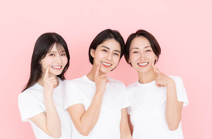 大人の女性三人が笑顔で歯を指差す様子