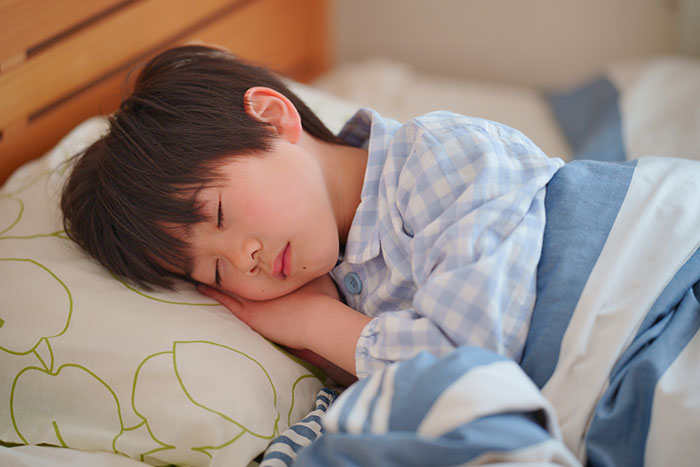 ベッドで睡眠中の小学生くらいの少年